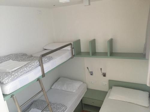 a small room with two bunk beds and a desk at Club del Sole Jesolo Family Resort in Lido di Jesolo