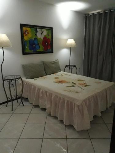 a bed in a room with two lamps and a painting on the wall at CASACOMPART itapuã in Salvador