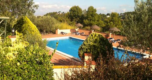 a large swimming pool with chairs and trees in the background at Hotel Golf Can Rafel in Corbera de Llobregat