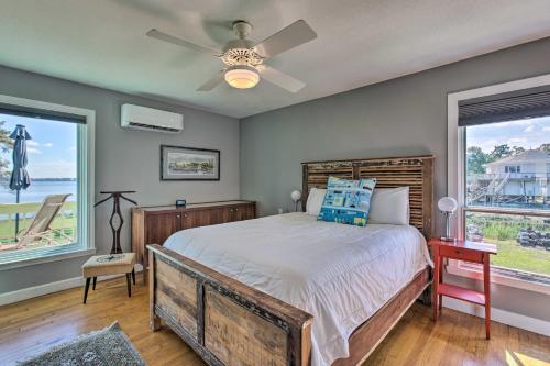 a bedroom with a bed with a ceiling fan and two windows at Riverfront New Bern House Gourmet Kitchen and View! in New Bern