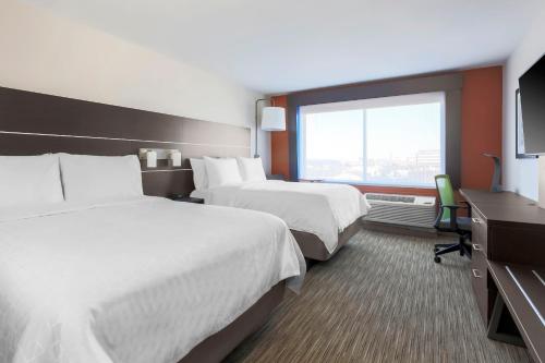 a hotel room with two beds and a window at Holiday Inn Express & Suites Chicago O'Hare Airport by IHG in Des Plaines