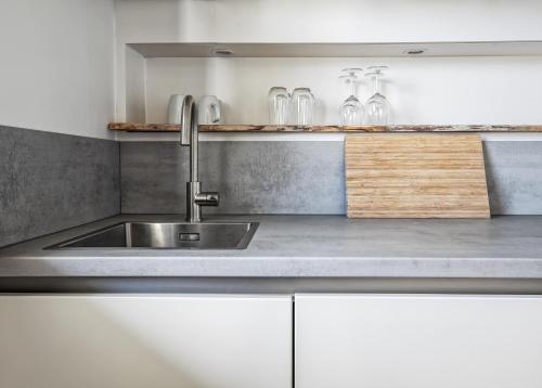 a kitchen with a stainless steel sink and white cabinets at Appartementen Sonnenhof in De Koog