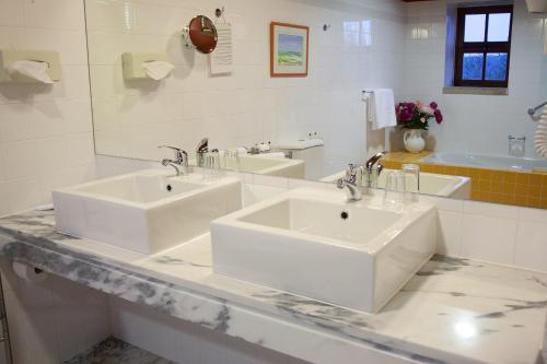 a white bathroom with two sinks and a mirror at Hotel Rural Quinta da Geia in Aldeia das Dez