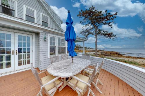 a table and chairs with an umbrella on a porch at Tranquil Ocean Retreat in Boothbay