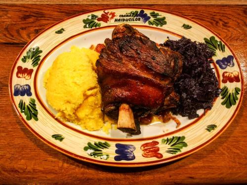 a plate of food with meat and potatoes on a table at Crama Haiducilor in Cluj-Napoca