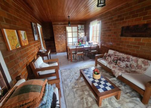 a living room filled with furniture and a brick wall at Chalé aconchegante na Serra Pernambucana - Em condomínio - Gravatá in Gravatá