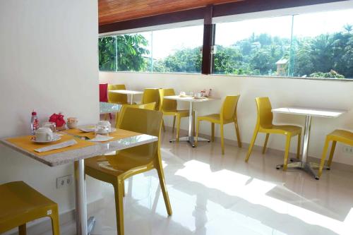 un ristorante con sedie e tavoli gialli e una grande finestra di Apart-Hotel Bella Vida Suítes e Apartamentos a Morro de São Paulo