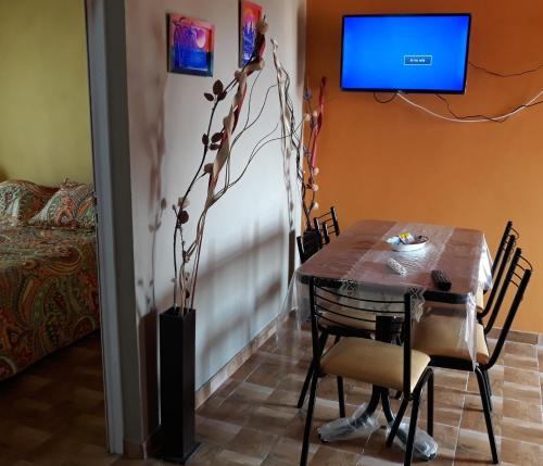 comedor con mesa y TV en la pared en Lo de Lio y Titi en San Clemente del Tuyú