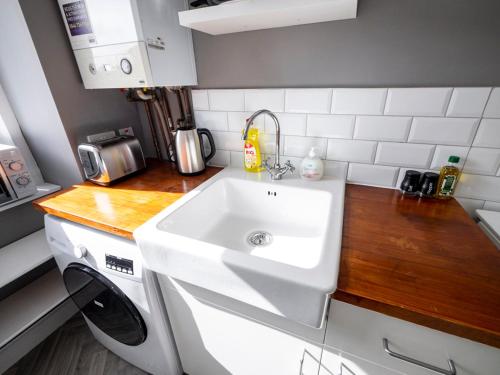 uma cozinha com um lavatório branco e um balcão em New Superhost Listing: Bright flat nr. University em Dundee
