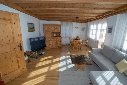 a living room with a couch and a tv at Chasa Nogler - Ferienwohnung in Ramosch
