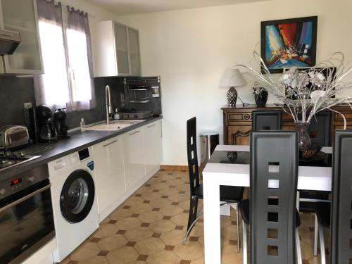 une cuisine avec une table et une machine à laver dans l'établissement Gîtes du Perey, à Jau-Dignac-et-Loirac
