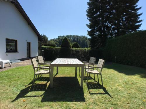 a table with four chairs around it in the grass at Villa Im Bongert - Tor zum Nationalpark Eifel in Hellenthal