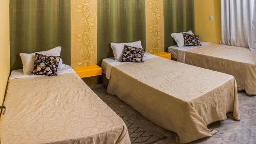 3 camas en una habitación con cortinas verdes en Ambiente familiar e confortável, en Foz do Iguaçu
