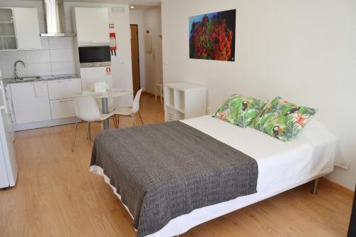 a bedroom with a bed and a table and a kitchen at Cerca da Vitoria 3 Milfontes in Vila Nova de Milfontes