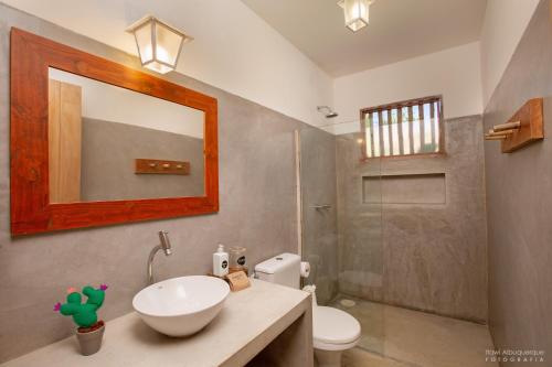a bathroom with a sink and a toilet and a mirror at Pousada Casotas in Pôrto de Pedras