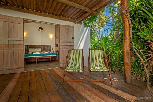 a bedroom with a bed and two chairs on a deck at Pousada Casotas in Pôrto de Pedras