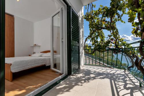 a bedroom with a bed and a balcony with a view at Apartmani Antonela in Drasnice
