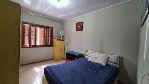 een slaapkamer met een blauw bed en een raam bij MARÉ - Paz e Sossego in Tramandaí