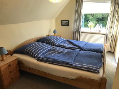 Schlafzimmer mit einem Bett mit blauer Bettwäsche und einem Fenster in der Unterkunft Ferienwohnung Heikendorf in Heikendorf