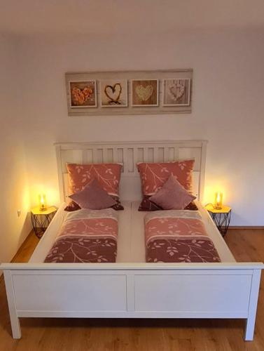 a large white bed in a bedroom with two lamps at Ferienwohnung am Waldsee mit Schwimmbad in Gernsbach