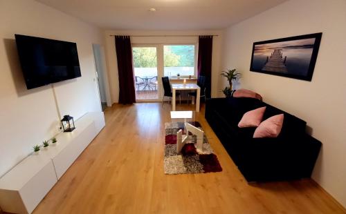 een woonkamer met een zwarte bank en een tafel bij Ferienwohnung am Waldsee mit Schwimmbad in Gernsbach