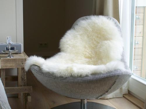 a white furry chair sitting in front of a window at Hotel het Oude Postkantoor in Brummen