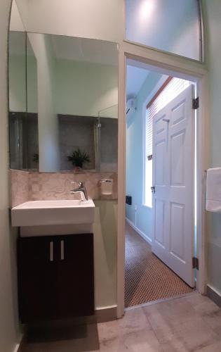 a bathroom with a sink and a mirror and a door at The Greenhouse Guesthouse in Cape Town
