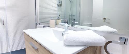 a white bathroom with a sink and a mirror at Sea to Sky Suites - Mijas Pueblo in Mijas