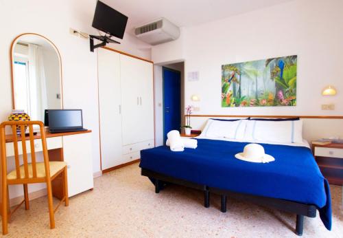 una camera da letto con un letto blu con due cappelli sopra di Hotel Adria B&B - Colazione fino alle 12 a Misano Adriatico