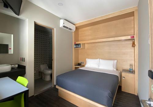 a small bedroom with a bed and a bathroom at Hotel MX zócalo CDMX, Trademark Collection by Wyndham in Mexico City