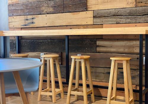 a bar with wooden stools in front of a wall at Hotel MX zócalo CDMX, Trademark Collection by Wyndham in Mexico City
