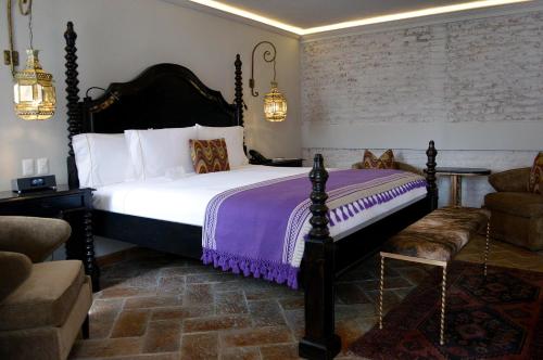 a bedroom with a large bed and a chair at Casa 1810 Hotel Boutique in San Miguel de Allende