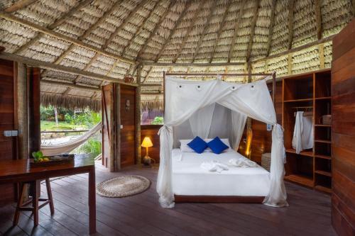 a bedroom with a bed with a mosquito net at Villa Sabiá - Eco Bungalows in Prea