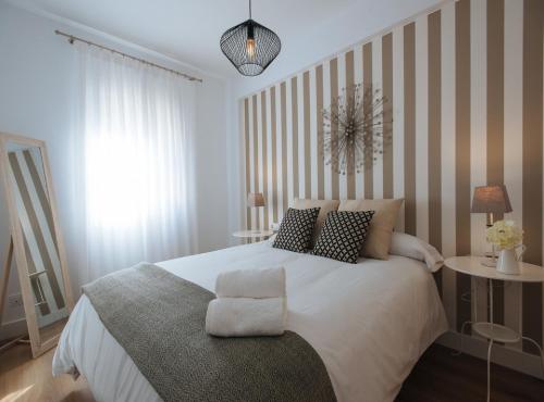 1 dormitorio con 1 cama blanca grande con silla en Magno Apartments Azahares, en Sevilla