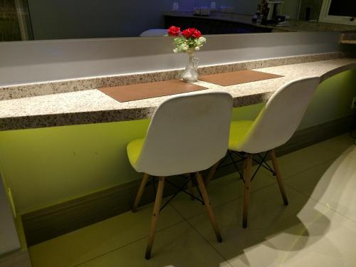 a kitchen counter with two chairs and a vase of flowers at A2 suites - Hotel e Motel in Brasilia