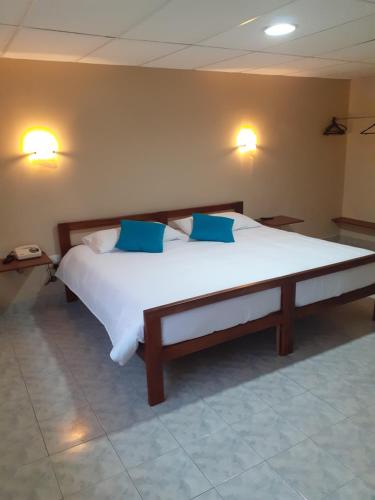 a bedroom with a large bed with blue pillows at El Balcon de los Reyes in Ibarra