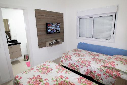 邦比尼亞斯的住宿－1067 - Apartamento para locação em Bombinhas com 03 suítes，卧室配有一张床,墙上配有电视。