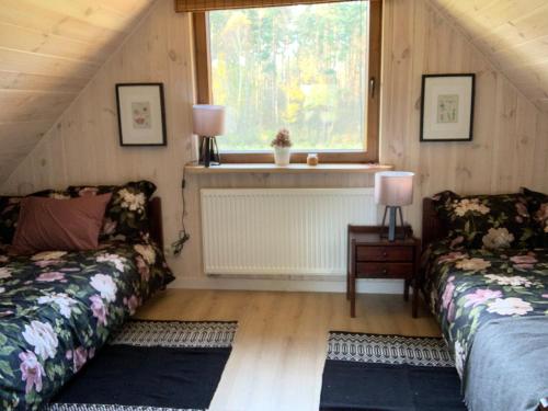 um quarto no sótão com 2 camas e uma janela em Fortuna Łazy em Goniadz