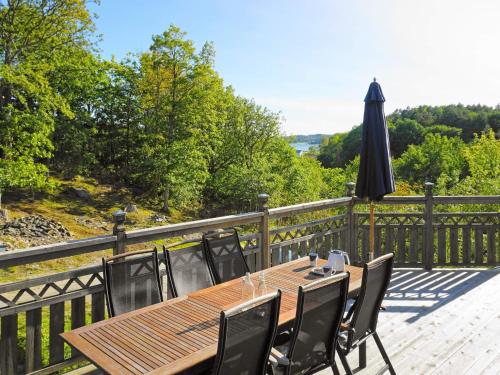 una mesa de madera con sillas y una sombrilla en una terraza en 9 person holiday home in ASKER ARNA, en Råssön