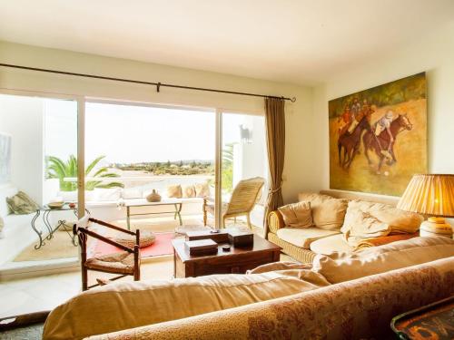 uma sala de estar com um sofá e uma pintura de cavalo na parede em Belvilla by OYO Apartment in SAN ROQUE CADIZ em Sotogrande