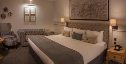 a hotel room with a large bed and a chair at Wotton House in Dorking
