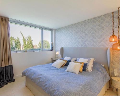 a bedroom with a blue bed with pillows and a window at Villa Infinity Denia in Denia