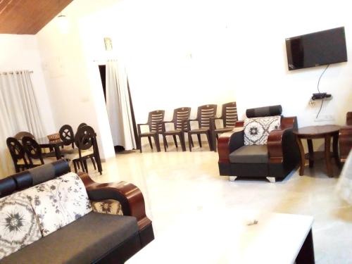 sala de estar con sofás y sillas y TV de pantalla plana. en Forest Sunrise Villa 3BHK, en Mahabaleshwar