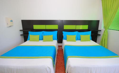 a bedroom with two beds with blue and green pillows at Glamping Girardot & Hotel Puerta Del Sol Girardot in La Virginia