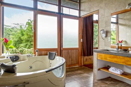 Kuyana Amazon Lodge في Archidona: حمام مع حوض كبير ومغسلة