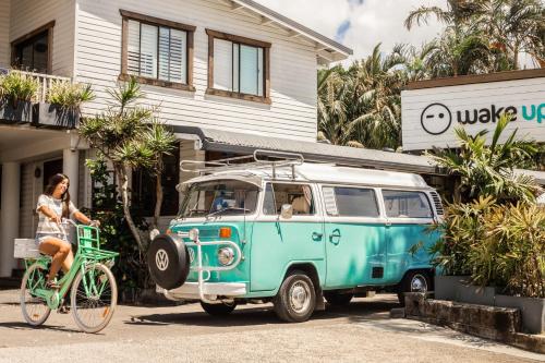 a woman riding a bike next to a van at Wake Up! Byron Bay in Byron Bay