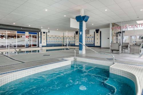 a swimming pool with blue water in a building at Super 8 by Wyndham Macleod Trail Calgary in Calgary