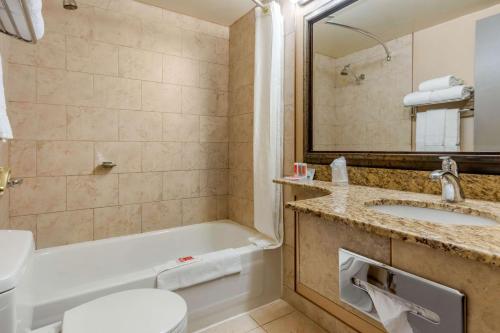 a bathroom with a tub and a sink and a toilet at Super 8 by Wyndham Macleod Trail Calgary in Calgary