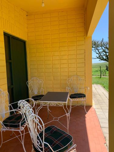 a patio with a table and chairs on a yellow wall at Tranquilo entorno campestre in Treinta y Tres