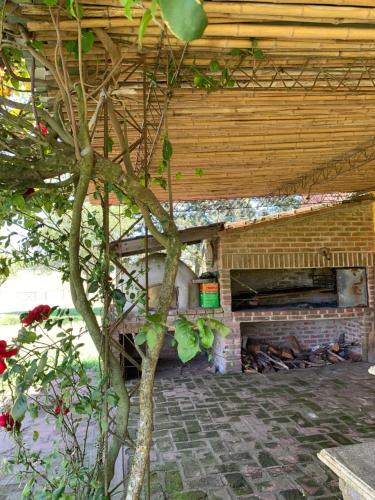 a patio with a brick fireplace under a wooden roof at Tranquilo entorno campestre in Treinta y Tres